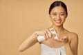 Studio portrait of pretty young woman smiling at camera, holding a bottle of gentle foam facial cleanser isolated over Royalty Free Stock Photo