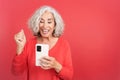 Mature woman celebrating while using the mobile phone Royalty Free Stock Photo