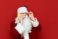 Studio portrait of Santa Claus phoning on red background and looking away. Santa talking on the phone. Isolated. New Year Royalty Free Stock Photo