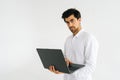 Studio portrait of serious confident young man holding in hand opened laptop computer and looking at camera standing on Royalty Free Stock Photo
