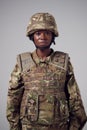 Studio Portrait Of Serious Young Female Soldier In Military Uniform Against Plain Background