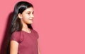 Studio portrait of smiling brunette child girl looking away on empty background of pastel pink color with copy space. Royalty Free Stock Photo