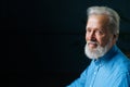 Studio portrait of smiling gray-haired senior man looking at camera on black isolated background. Royalty Free Stock Photo