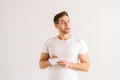 Studio portrait of smiling pensive young man writing in copybook on white  background, looking away. Royalty Free Stock Photo