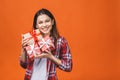 Studio portrait of smiling young beautiful woman holds red gift boxes. Isolated against orange background Royalty Free Stock Photo