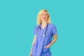 Smiling young female doctor or nurse wearing blue scrubs,  in studio Royalty Free Stock Photo