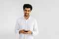 Studio portrait of smiling young man in casual shirt looking at camera holding smartphone, using online mobile apps Royalty Free Stock Photo