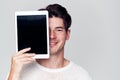 Studio Portrait Of Smiling Young Man Covering Face With Digital Tablet Royalty Free Stock Photo