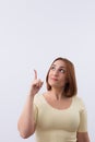 Studio portrait of smiling young woman looking and pointing finger up isolated on white background. Royalty Free Stock Photo