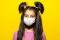 Studio portrait of teenager girl wearing medical mask on yellow background. Prevention of coronavirus and covid-19. Royalty Free Stock Photo