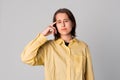 Studio portrait of a thinking pose girl touching herself head by index finger, dressing in stylish yellow shirt. Concept of Royalty Free Stock Photo