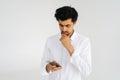 Studio portrait of thoughtful bearded business man holding smartphone, using online mobile apps, looking on device Royalty Free Stock Photo