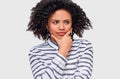 Studio portrait of thoughtful young woman with dark shaggy hair touching her chin and looking at one side with sceptical Royalty Free Stock Photo