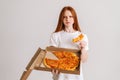 Studio portrait of unhappy young woman eating bad quality pizza holding box in hands looking at camera standing on white Royalty Free Stock Photo