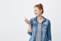 Studio portrait of upbeat positive young ginger girl looking at smartphone screen while listening music or watching
