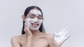 A studio portrait with a white backdrop shows a Filipina transwoman enjoying applying the foamy soap as she gently exfoliates the Royalty Free Stock Photo