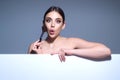 Studio portrait of a woman applying cosmetic tonal foundation on face using makeup brush. Beautiful girl doing Royalty Free Stock Photo