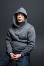 Studio portrait of a 40-50-year-old serious man in a gray hoodie on a neutral background with a hood on his head, looking at the c Royalty Free Stock Photo
