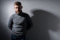 Studio portrait of a young bearded guy of twenty-five years old. In a warm winter sweater, proudly, gray, looks away. On a black