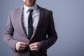 Studio portrait of a young bearded handsome guy of twenty-five years old, in an official suit, buttoning a button in a jacket. On