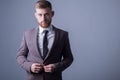 Studio portrait of a young bearded handsome guy of twenty-five years old, in an official suit, buttoning a button in a jacket. On