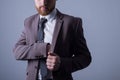 Studio portrait of a young bearded handsome guy of twenty-five years old, in an official suit, sticks his hand in the inside