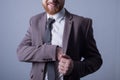 Studio portrait of a young bearded handsome guy of twenty-five years old, in an official suit, sticks his hand in the inside