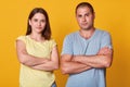 Studio portrait of young beautiful couple marrieds with unhappy faces and negative emotions stare directly at camera with hands