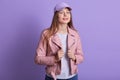 Studio portrait of young beautiful fashionable model wearing pink leather jacket, white shirt and cap. Women fashion and lifestyle Royalty Free Stock Photo