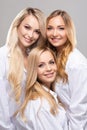 Studio portrait of young, beautiful and natural blond women over grey background. Close-up of smiling girls. Face Royalty Free Stock Photo