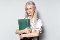 Studio portrait of young blonde cute teenager girl holding a folder in hands on white background Royalty Free Stock Photo