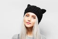 Studio portrait of young blonde pretty girl wearing black hat with cat ears on white background. Royalty Free Stock Photo