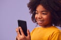 Studio Portrait Of Young Boy Using Mobile Phone Against Purple Background Royalty Free Stock Photo