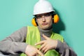 Studio portrait of young cool builder man, engineer dancing, wearing construction safety headphones, hard helmet.