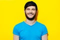 Studio portrait of young guy in blue shirt with beanie hat on background of yellow color. Royalty Free Stock Photo