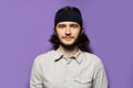 Studio portrait of young handsome man, with long brown hair and confident attitude. On the background of purple wall. Royalty Free Stock Photo