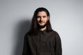 Studio portrait of young handsome man with long hair, on the grey background Royalty Free Stock Photo