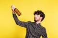 Studio portrait of a young man holding a bottle on a yellow background. Royalty Free Stock Photo