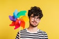 Studio portrait of a young man holding a windmill on a yellow background. Royalty Free Stock Photo