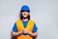 Studio portrait of young happy construction worker engineer on the background of grey wall. Wearing safety equipment; blue hard. Royalty Free Stock Photo