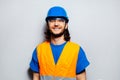 Studio portrait of young happy construction worker engineer wearing safety equipment; blue hard hat, transparent goggles. Royalty Free Stock Photo