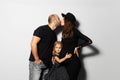 Studio portrait of young happy family, mother and father kissing, daughter hugging belly, on white background. Royalty Free Stock Photo