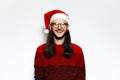 Studio portrait of young happy man in red sweater, wearing Santa Claus hat and eyeglasses. Isolated on white background Royalty Free Stock Photo