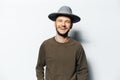 Studio portrait of young laughing man on white background, wearing sweater and grey hat Royalty Free Stock Photo