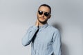 Studio portrait of young man, wearing sunglasses and blue shirt on white background Royalty Free Stock Photo