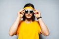 Studio portrait of young man wearing sunglasses, yellow band for head and shirt on background of grey textured wall. Royalty Free Stock Photo