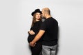 Studio portrait of young parents, pregnant woman wearing black hat and dress, man touching the belly on white background. Royalty Free Stock Photo