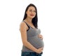 Studio portrait of young pregnant brunette woman in shirt touching her belly and looking at the camera isolated on white Royalty Free Stock Photo