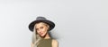 Studio portrait of young pretty blonde girl with wireless earbuds in ear, wearing grey hat on white background. Panoramic banner Royalty Free Stock Photo