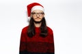 Studio portrait of young sad man in red sweater, wearing Santa Claus hat and eyeglasses. Isolated on white background. Royalty Free Stock Photo